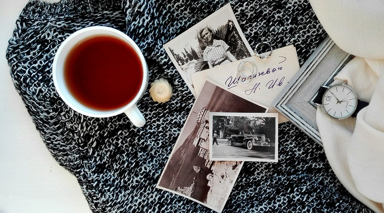 A collection of photos atop a knit blanket with a cup of tea and some jewelry