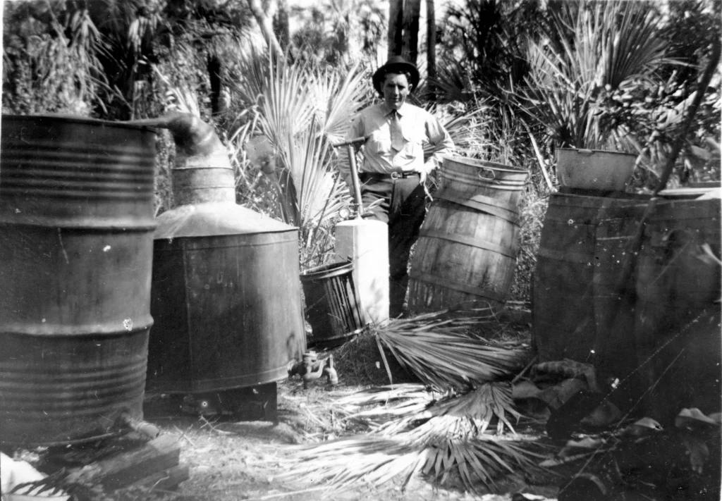 Black and White, a man standing alongside moonshine barrels