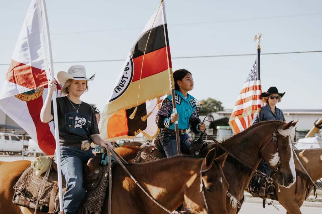Three girls on horses bearing the Florida, Seminole Tribe of Florida, and United States Flags