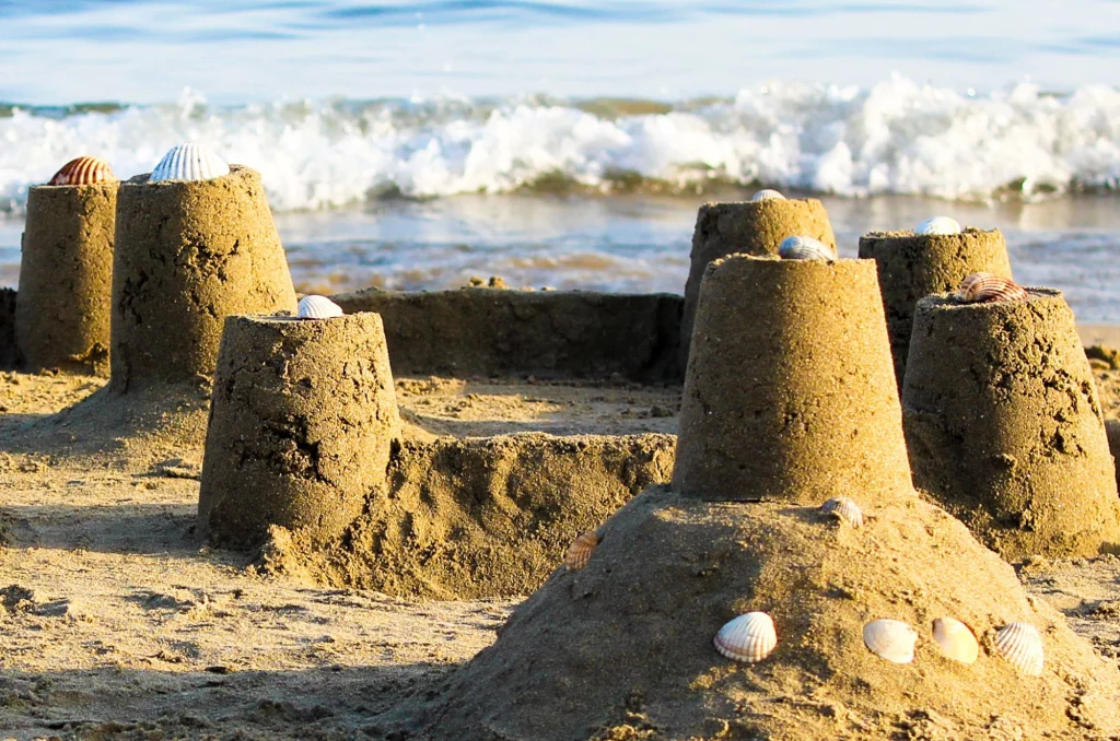 Close up of a sandcastle in front of breaking waves