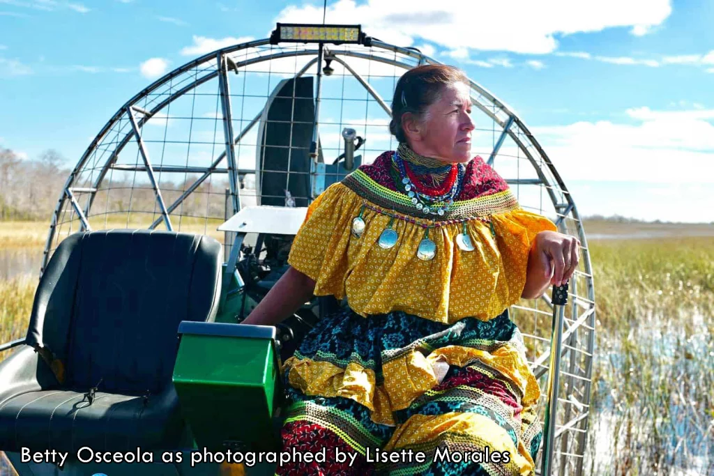 Betty Osceola on an airboat in traditional dress as photographed by Lisette Morales
