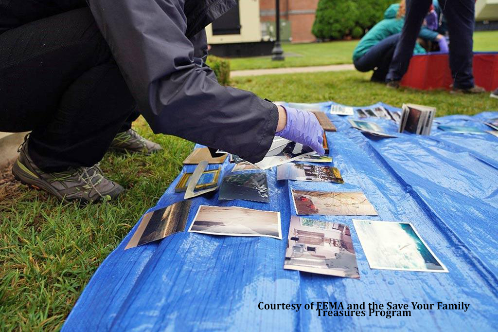 Gloved hands cleaning photographs on a blue tarp