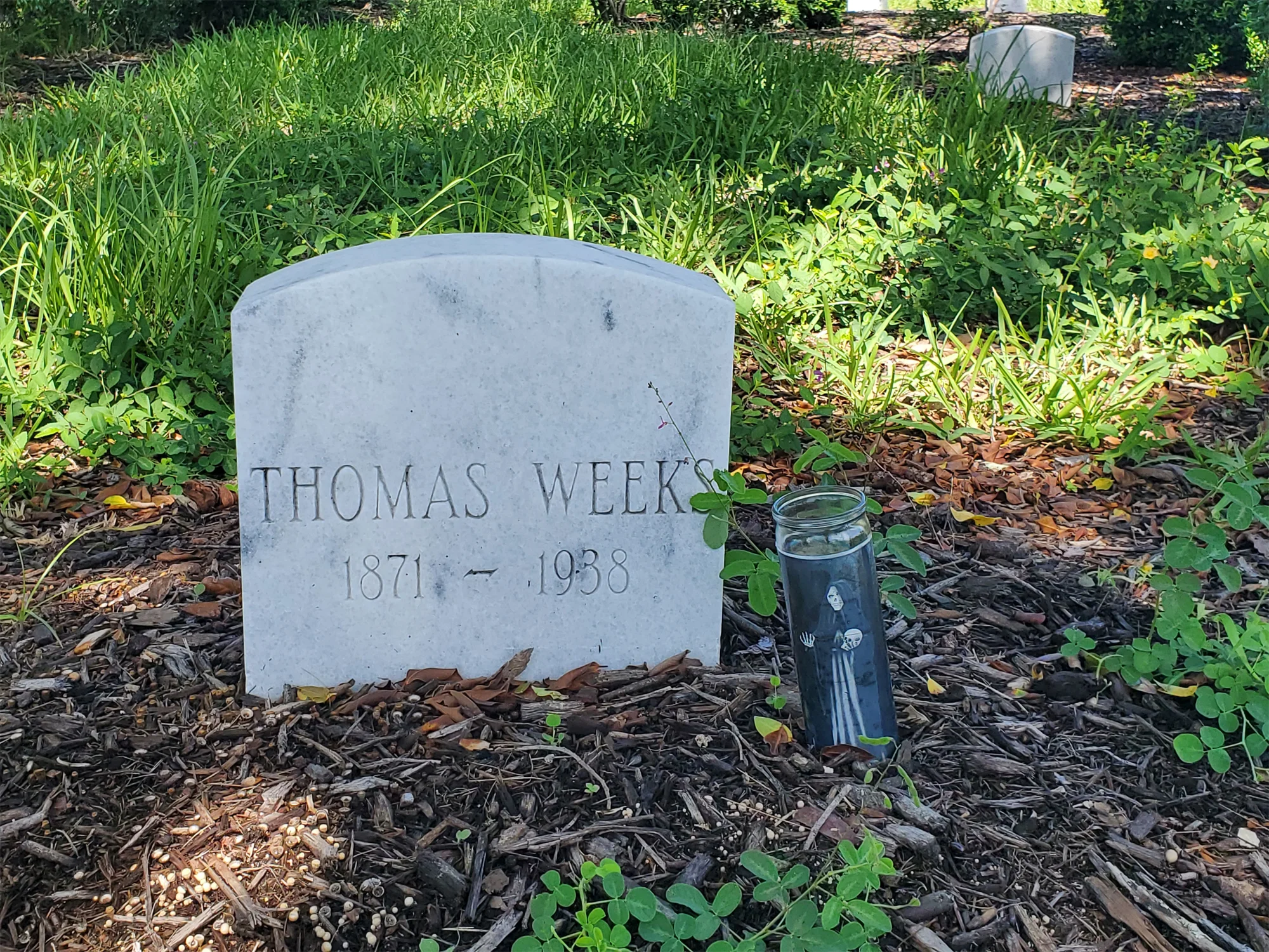 Gravestone on dirt and a tall black candle sporting a Grim Reaper graphic